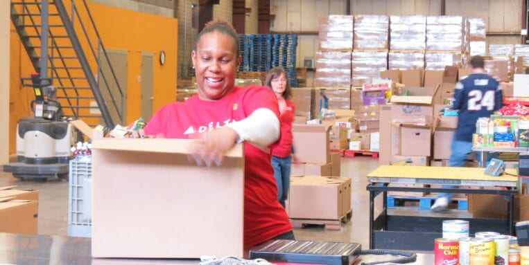 At Food Bank of CNY, a woman packs a box of food.