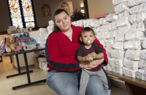 Mother holds baby next to a pile of diapers