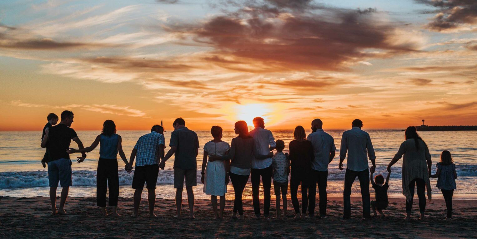 family standing at beach at sunset