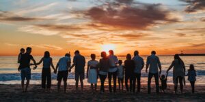 family standing at beach at sunset