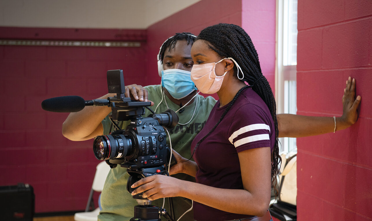 Man helping young lady with camera