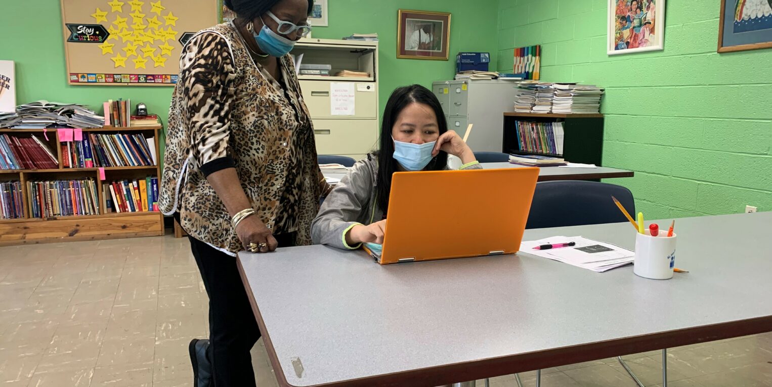 Woman standing over woman on computer