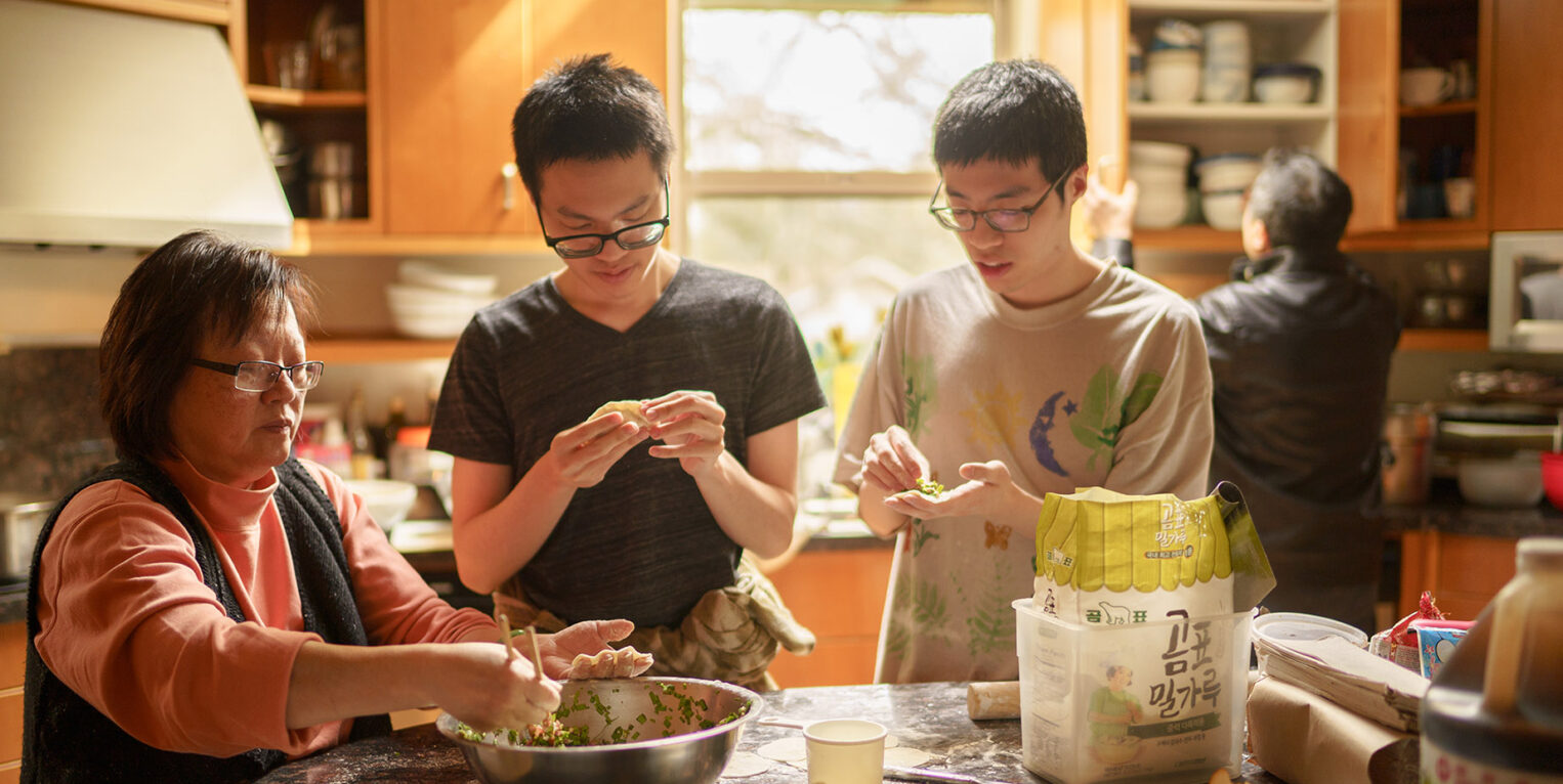 Family members prepare food around a kitchen counter