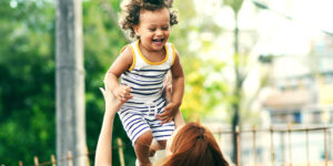 Woman holds baby up in the air