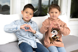 Girl and boy holding up heart hand gestures