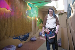 Woman holding up young boy walking