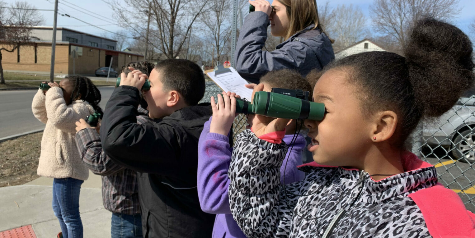 Children looking through binoculars on Syracuse street