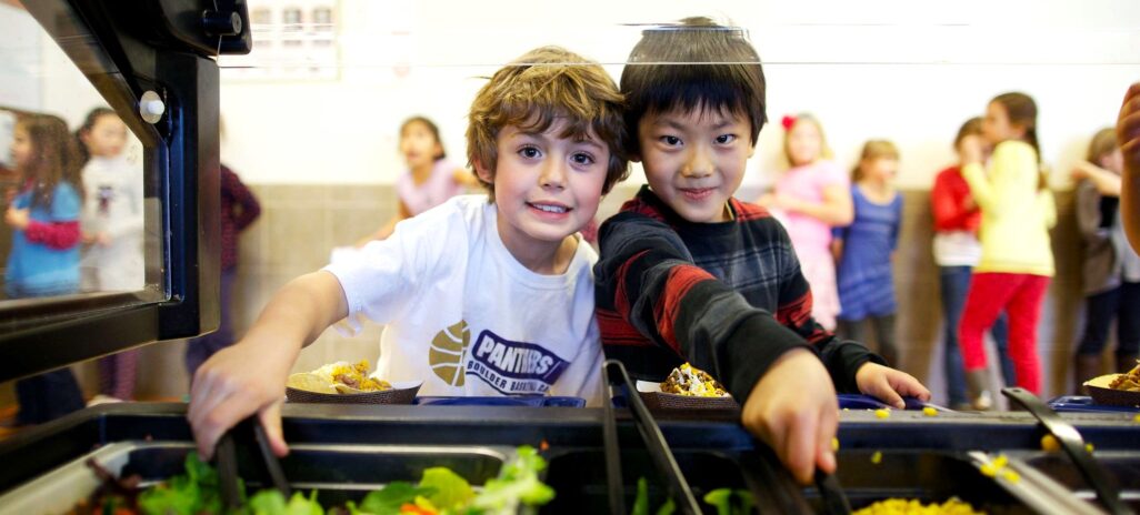 Two kids serving themselves salad
