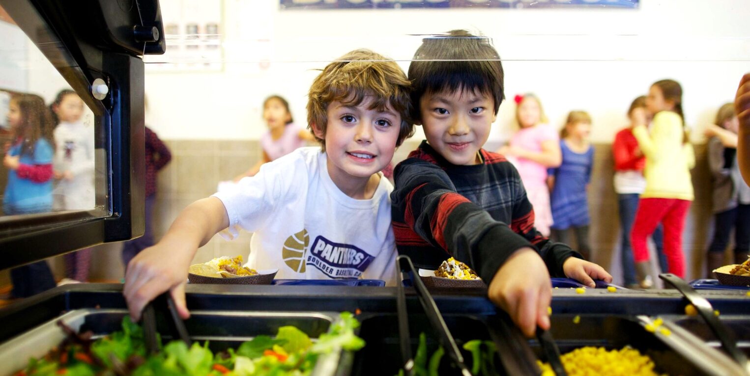 Two kids serving themselves salad