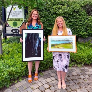 Two people standing and holding artwork