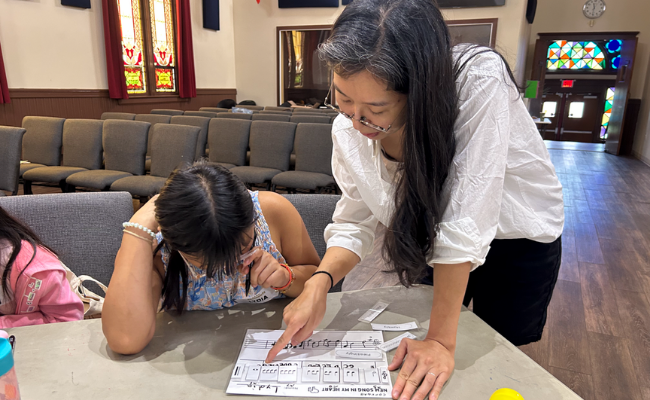 Person helping child at a desk with paper