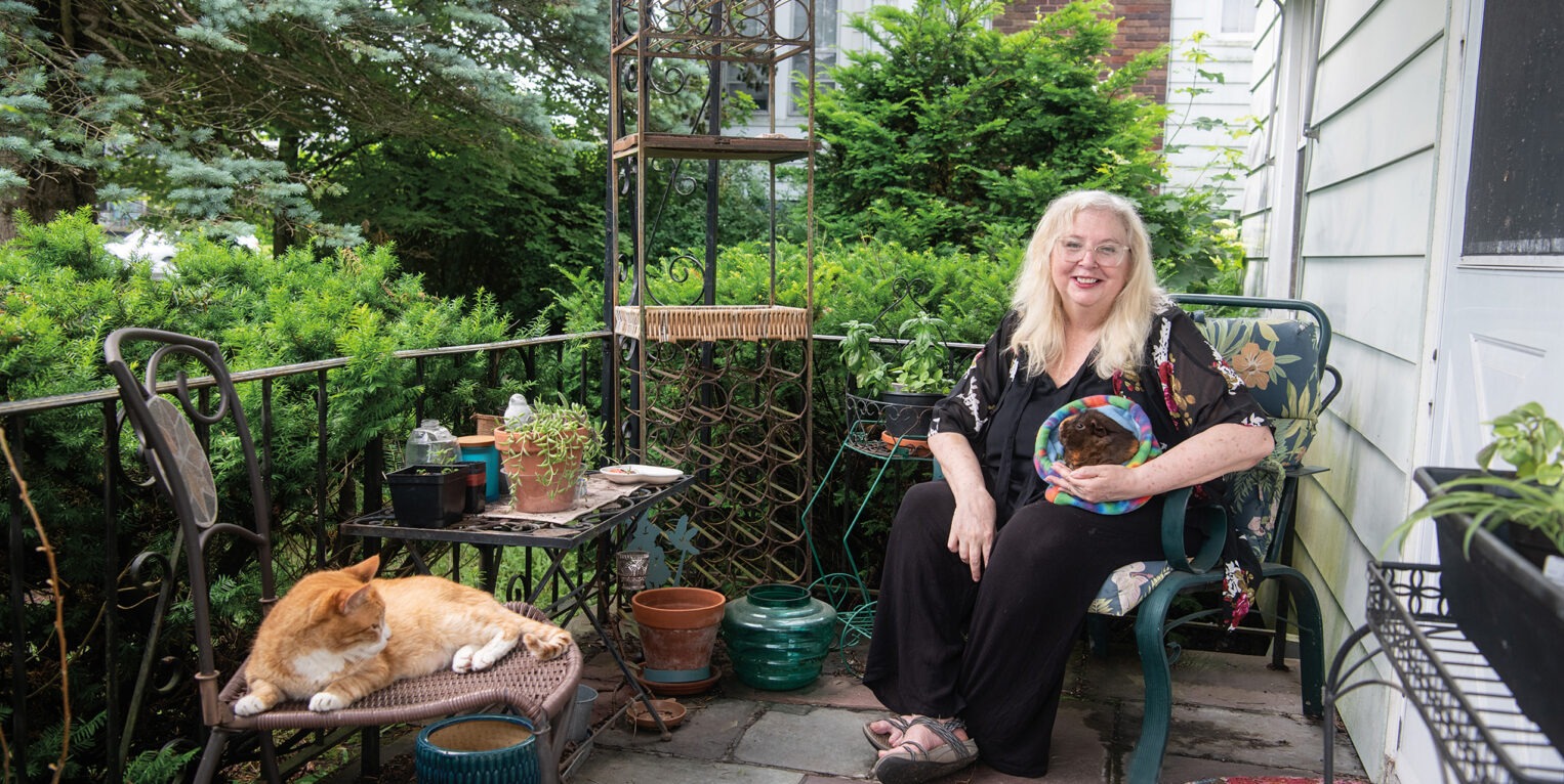Woman sitting on her porch with her cat and guinea pig